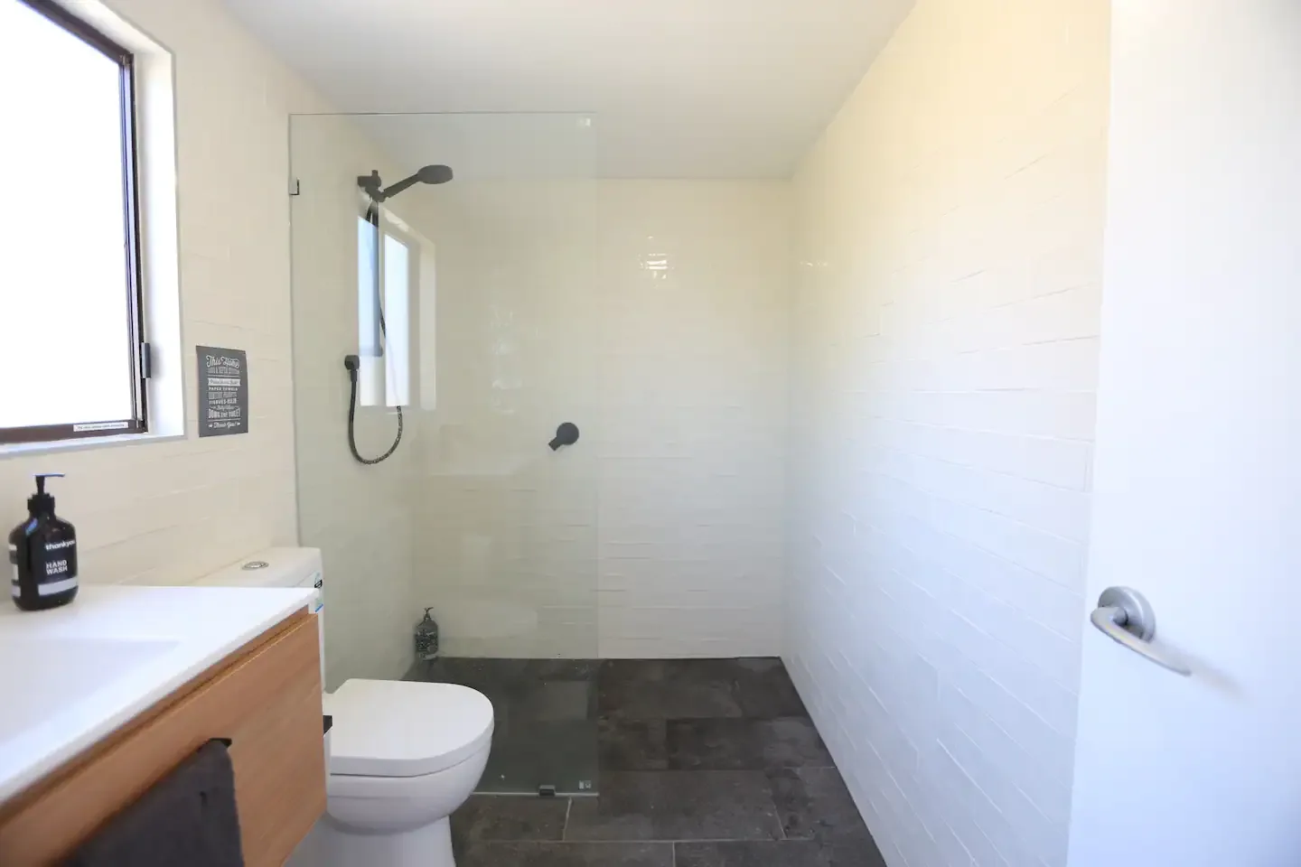 Renovated bathroom with walk in shower and wall hung vanity, suited to an established brick home
