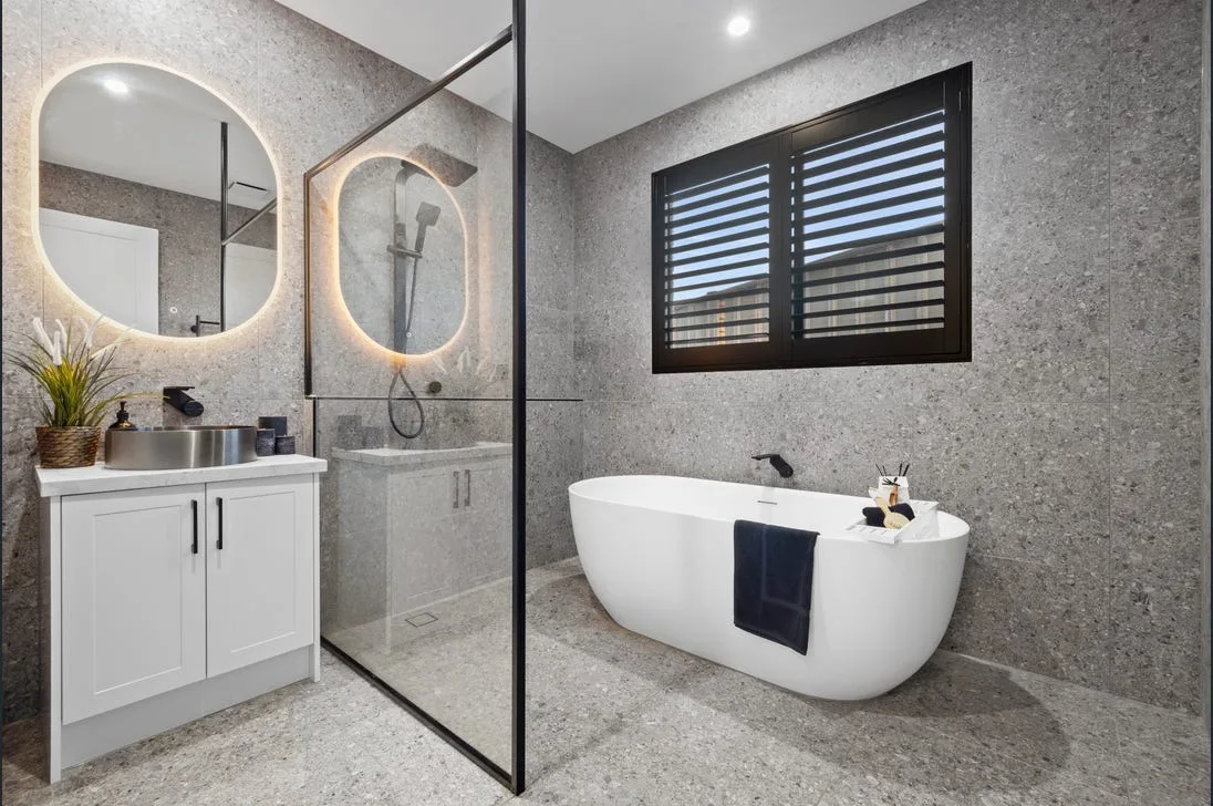 Renovated bathroom with freestanding bath and twin backlit mirrors