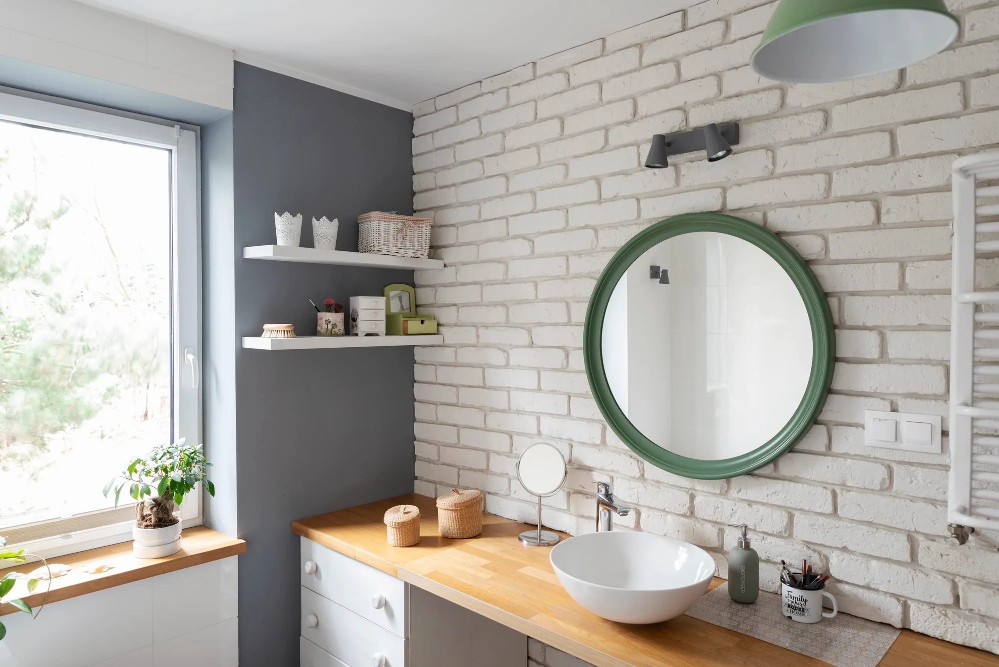 Custom designed bathroom with round green mirror, painted brick wall and timber bench