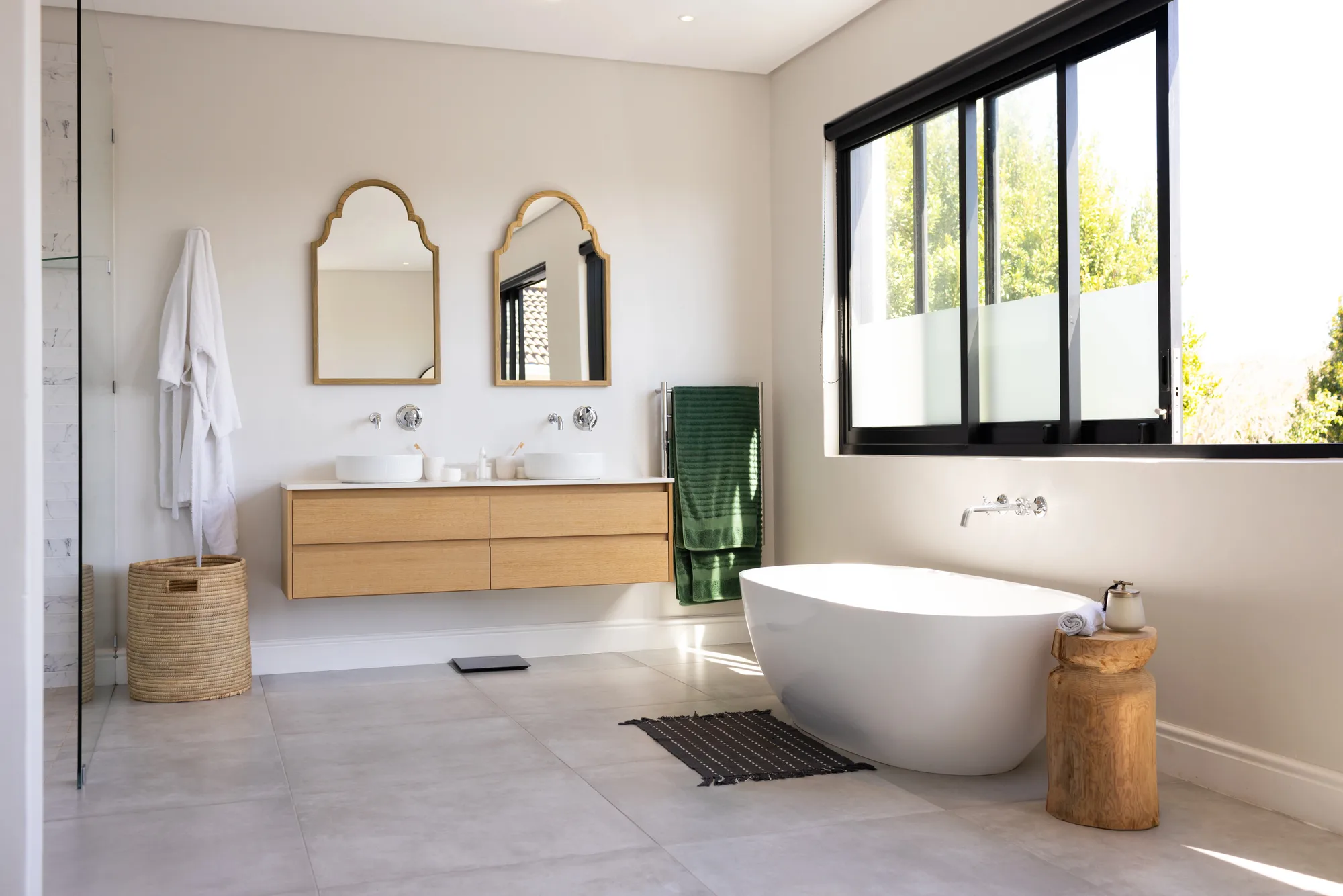 Luxury bathroom with freestanding bathtub, arched mirrors and timber vanity